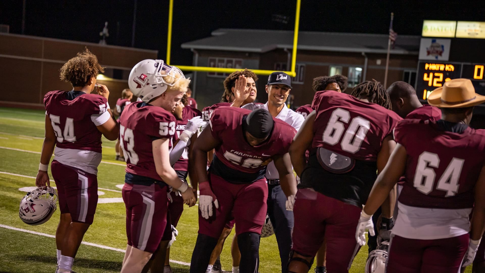 Michael Fasusi and co-offensive coordinator Nate Blackwell celebrate on the field after a 2023 LHS football game.